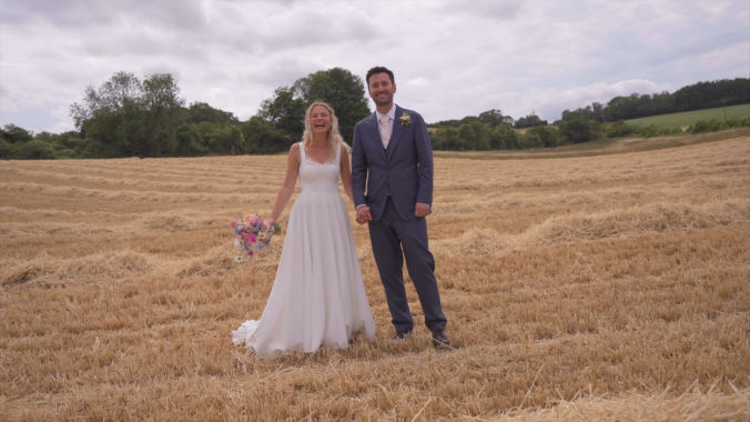 bride and groom standing in cut down summer wheat field